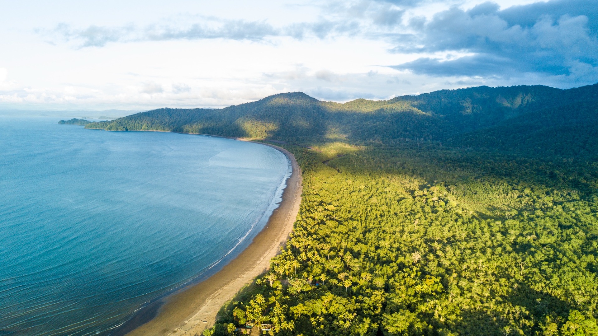 Aerial view of a pristine coastal development site with turquoise waters and forested hills