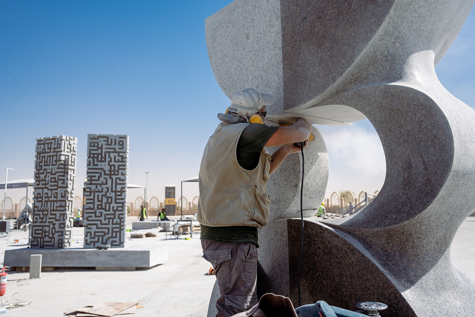 Worker finishing a monumental granite sculpture on site in Riyadh