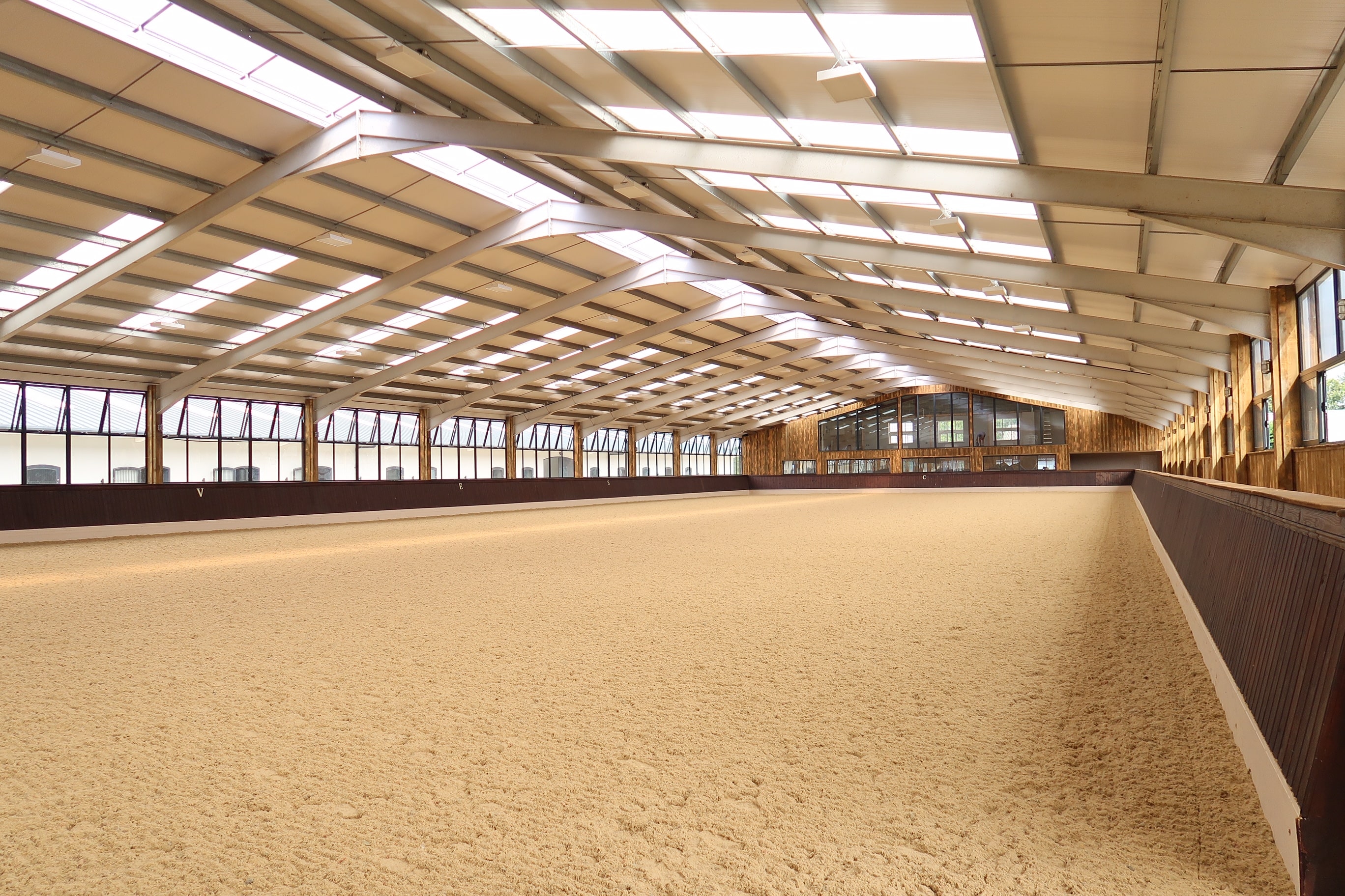 Modern covered arena with sand surface and tiered grandstands